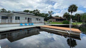 En ejendom ved vandet med bådebro, hus og swimmingpool.