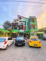 Un edificio de varios pisos con fachada verde y blanca, un letrero visible que dice 'BINANGA', y un coche estacionado adelante.