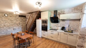 A kitchen with a wooden dining table, chairs, a refrigerator, oven, and a built-in stove. - Burgundian loft at the foot of the Seine springs (Chanceaux)