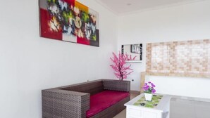 Ein modernes Wohnzimmer mit einer grauen Couch, einem weißen Couchtisch und einem farbenfrohen abstrakten Gemälde an der Wand.