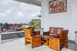 Ein Balkon mit Holzmöbeln, einem Gemälde und Blick auf Gebäude.