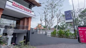 Ein RedDoor Hotel mit moderner Fassade, einem Schild für Uluwatu Suites und einer angelegten Gartenanlage.