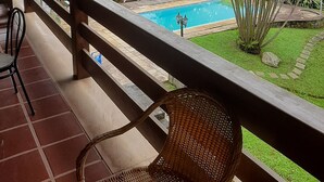 Ein Balkon mit Blick auf einen Pool, der von üppigem Grün umgeben ist.