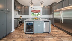 A modern kitchen with grey cabinets, stainless steel appliances, and a central island. - Your Perfect Southwest Michigan Lakehouse Getaway (Paw Paw)