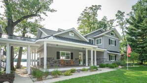 A two-story house with a covered porch, stone accents, and a flag. - Your Perfect Southwest Michigan Lakehouse Getaway (Paw Paw)