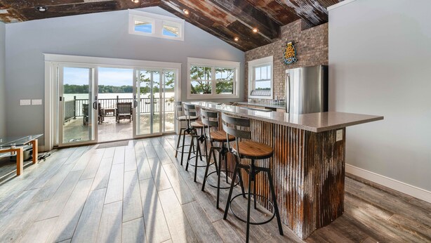 A spacious kitchen with a rustic bar area, large windows, and a view of the outdoors. - Your Perfect Southwest Michigan Lakehouse Getaway (Paw Paw)