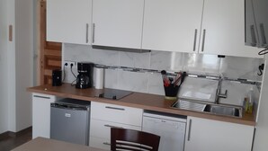 A modern kitchen with white cabinets, a wooden countertop, and a built-in dishwasher. - La maison verte, a charming and modern two-room apartment (Strasbourg)
