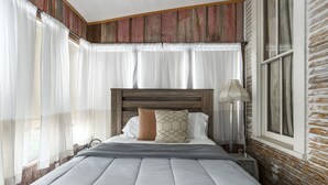 A neatly made bed with a wooden headboard, white and beige pillows, and a gray blanket.