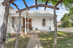 A white house with a porch, wooden beams, and a mailbox.