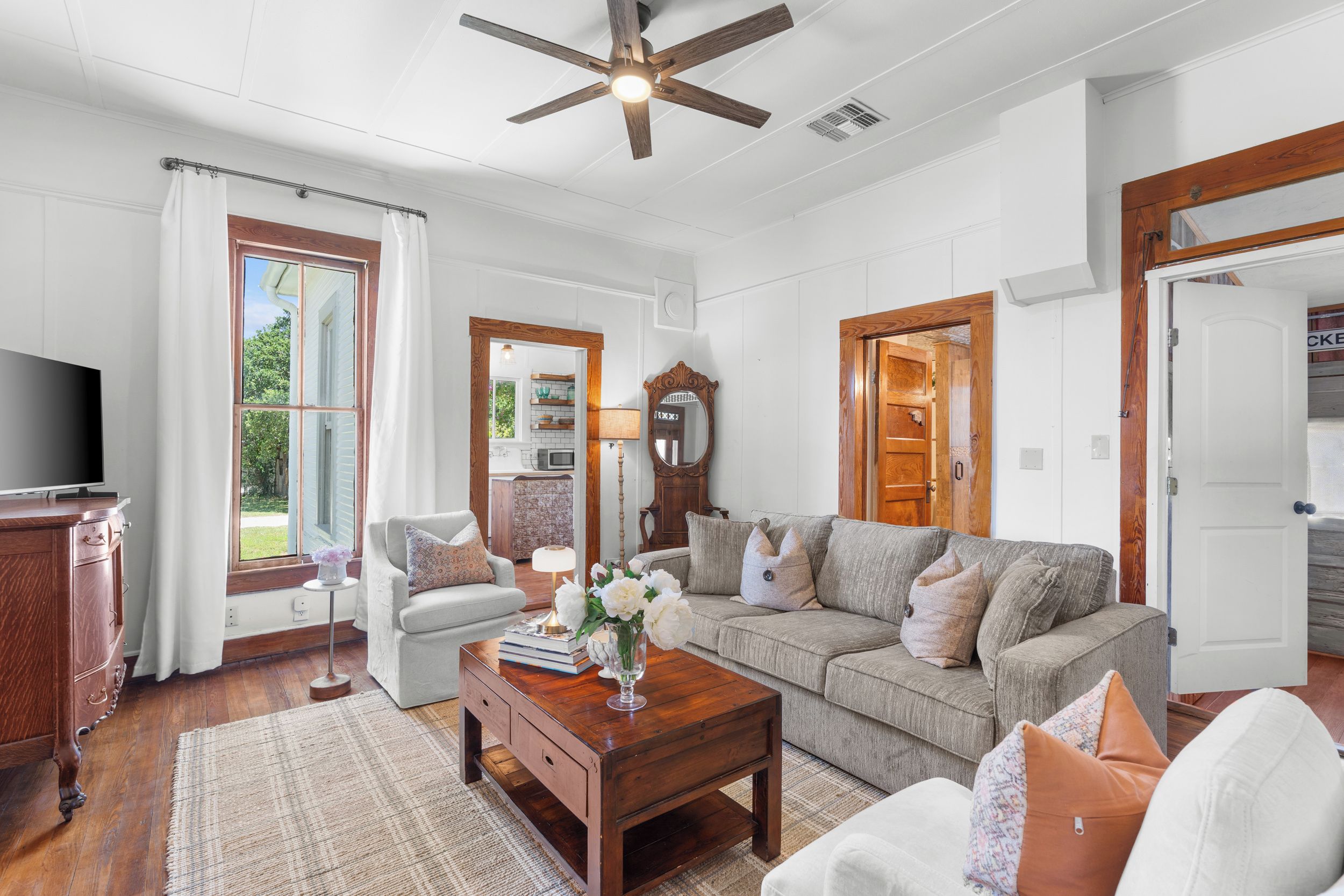 A living room with a television, sofa, coffee table, and a ceiling fan.