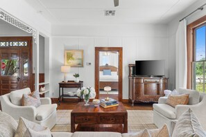 A spacious living room with a large television, comfortable seating, and a view of the outdoors.