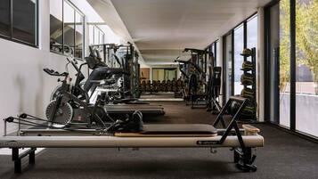 A gym with exercise equipment, a rowing machine, and dumbbells.