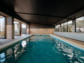 A modern indoor swimming pool with a wooden ceiling, large windows, and a clear view of the outside. - Mercure Melbourne Doncaster (Doncaster)