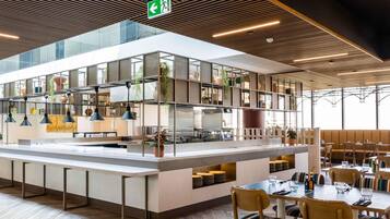 A modern restaurant with a central island, seating area, and a ceiling with linear lighting.