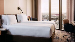 A hotel room with a large bed, a desk with a chair, and a view of the city through large windows. - Mercure Melbourne Doncaster (Doncaster)