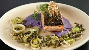 A plate with salmon, capers, and purple potatoes.