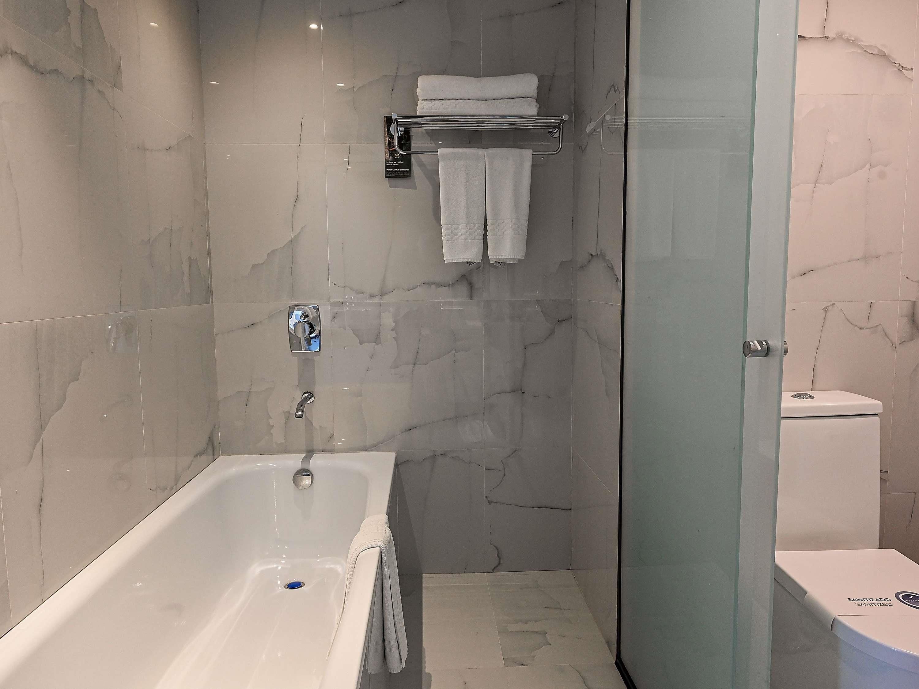 A modern bathroom with a bathtub, a glass shower enclosure, and a toilet.