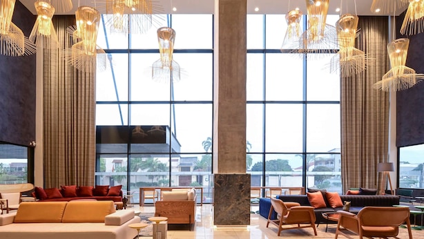 Un hall de hotel espacioso con muebles modernos, ventanas amplias que ofrecen vistas a la ciudad y lámparas colgantes originales.