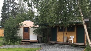 A rustic cabin with a wooden exterior, a covered porch, and a gravel pathway leading to the entrance.