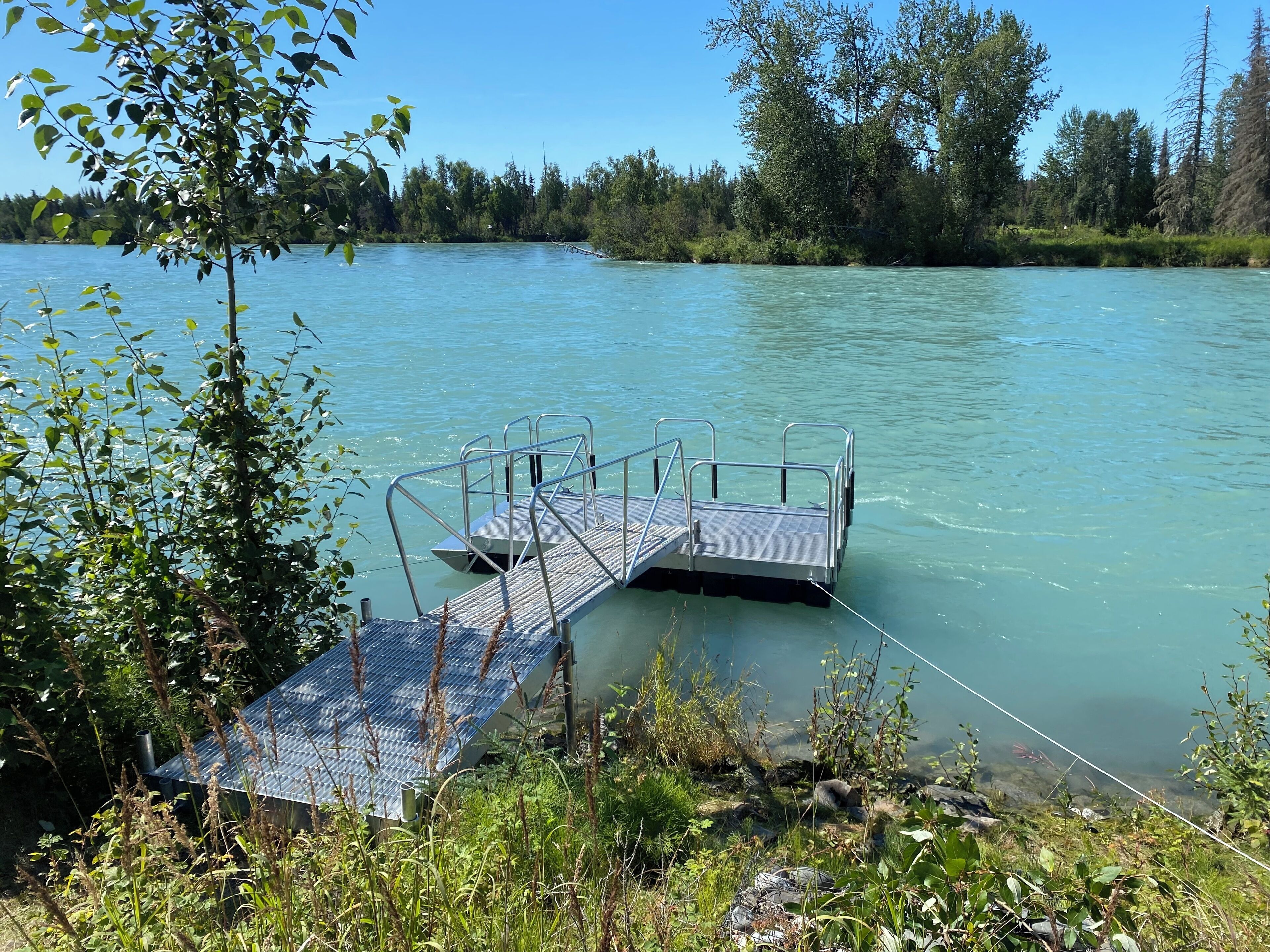 Une jetée s’avançant dans une étendue d’eau calme, entourée d’une végétation luxuriante et d’arbres.