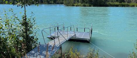 Une jetée s’avançant dans une étendue d’eau calme, entourée d’une végétation luxuriante et d’arbres.