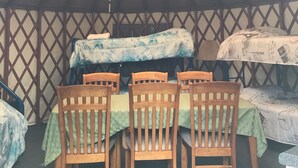 A tented room with a dining table and chairs, a hanging light fixture, and a patterned wall.