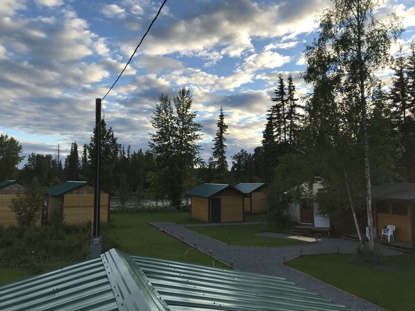 Ein Campingplatz mit mehreren Holzhütten, einer Rasenfläche und einem bewölkten Himmel.