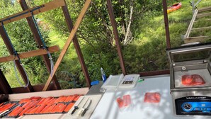 A seafood preparation area with a vacuum sealer, knives, and a Kingsford bag.