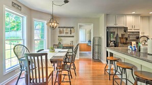 A modern kitchen with wooden flooring, a dining area with a table and chairs, and a bar area with stools.