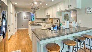 A kitchen with white cabinets, a granite countertop, and a central island with stools.