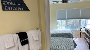Ein Schlafzimmer mit zwei Betten, einem Deckenventilator und einem Fenster mit Jalousien.