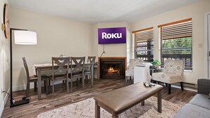 Un salon avec une cheminée, un coin repas avec une table et des chaises, et un canapé.