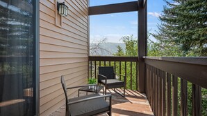 Un espace extérieur abrité doté d’une terrasse en bois, de deux chaises et d’une table.