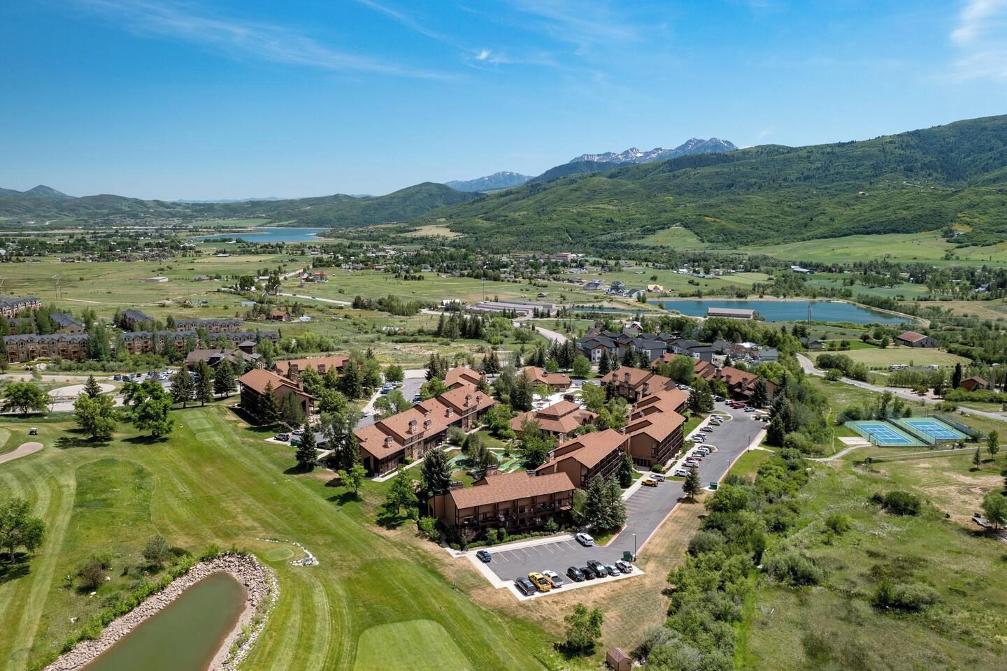 A residential area with multiple houses, a golf course, and a lake.