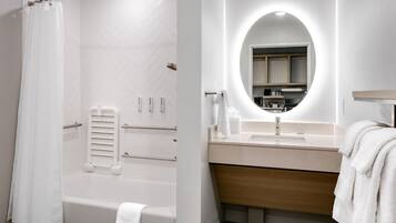 A modern bathroom with a shower, a vanity with a mirror, and a towel rack.