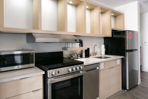 A modern kitchen with stainless steel appliances, wooden cabinets, and a built-in oven. - TownePlace Suites by Marriott Madison West/Middleton (Middleton)