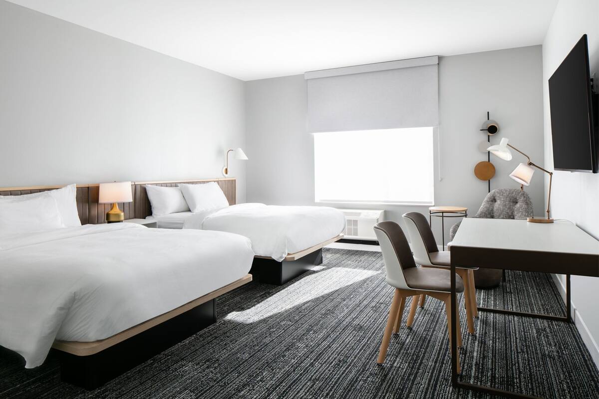 Hotelkamer met twee bedden, een bureau, een stoel, een televisie en een raam met uitzicht.