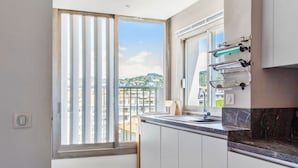 A modern kitchen with a large window, a sink, and a marble countertop. - Le Panoramique Croisette - Welkeys (Cannes)