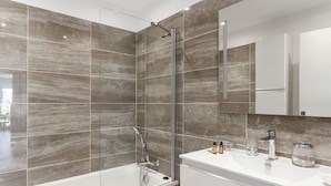 A modern bathroom with a glass-enclosed shower, a white bathtub, and a vanity with a mirror. - Le Panoramique Croisette - Welkeys (Cannes)