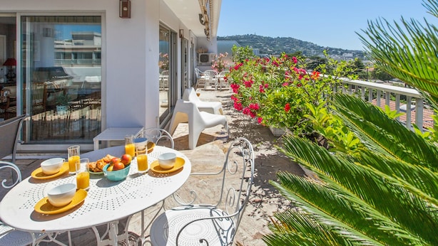 An outdoor dining area with a table set for breakfast, including bowls, glasses, and croissants. - Le Panoramique Croisette - Welkeys (Cannes)