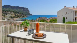 Ein Balkon mit Frühstückstisch, der Blick auf die Küste mit Gebäuden und Klippen freigibt.