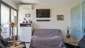 Ein modernes Wohnzimmer mit einer Couch, zwei Sesseln, einem Fernseher und einem kleinen Schrank.