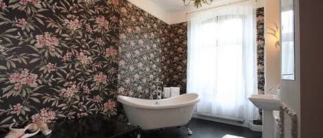 A bathroom with a freestanding bathtub, a sink, and a mirror.
