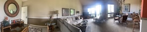 A spacious living room with a large sofa, a coffee table, and a dining area with chairs.