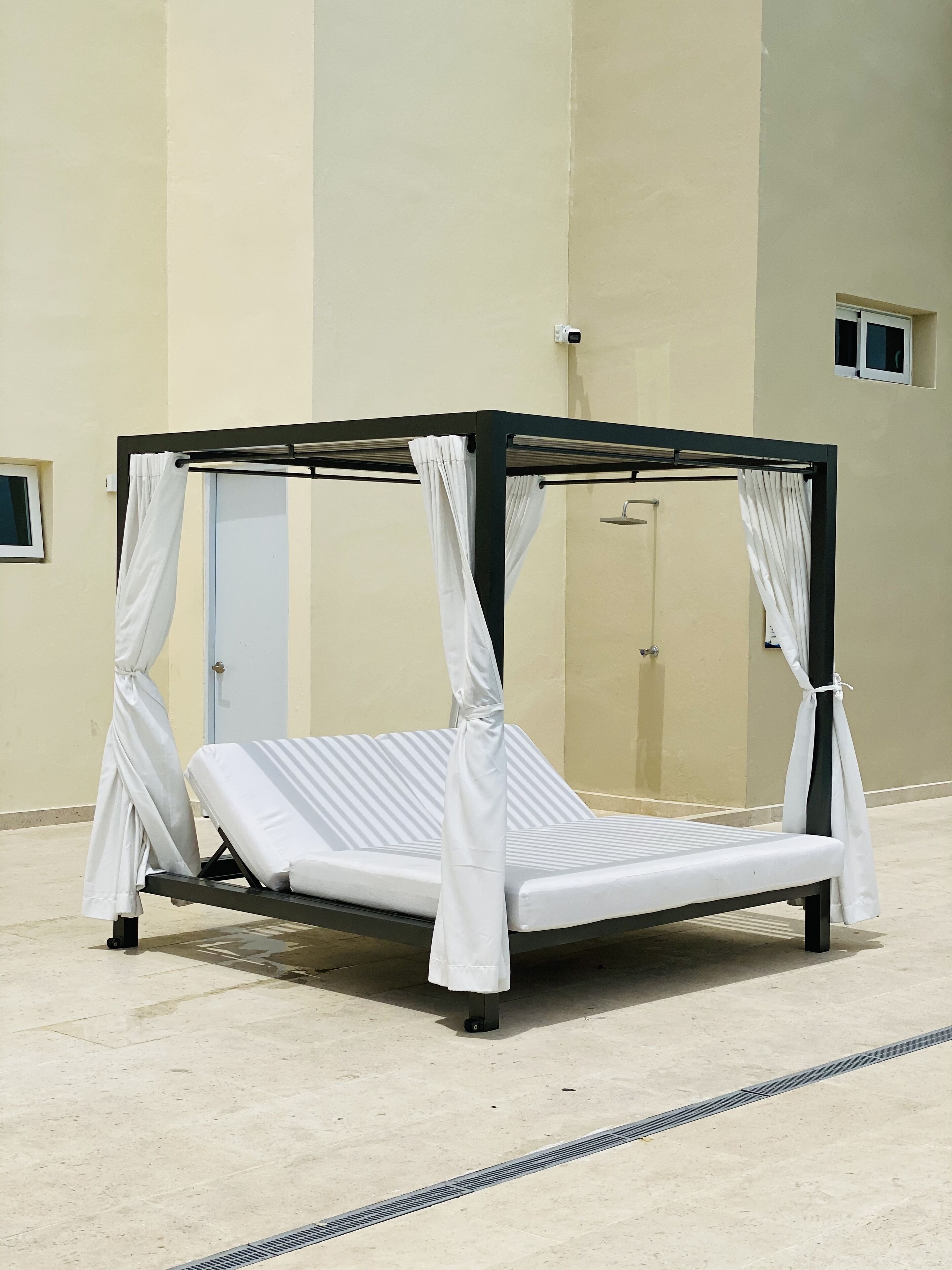 A single bed with a canopy, a door, and a small window.