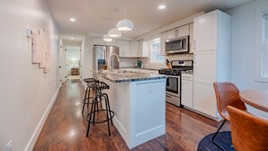 A modern kitchen with a central island, bar stools, stainless steel appliances, and pendant lighting. - The Johnson Chalet in Bristol/Canandaigua*HOT TUB* (Canandaigua)