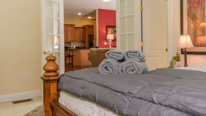 Une chambre à coucher avec un lit, une tête de lit en bois et une vue sur la cuisine.
