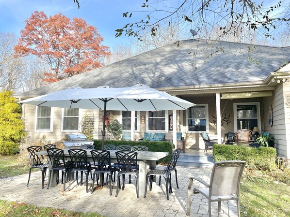 A patio with a table and chairs, a grill, and a covered area with a white umbrella. - Central to Mystic and Vineyards (Stonington)