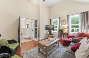 A living room with a television, a sofa, a coffee table, and a door leading to another room.