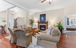 A spacious living room with a fireplace, two sofas, a coffee table, and wicker chairs.